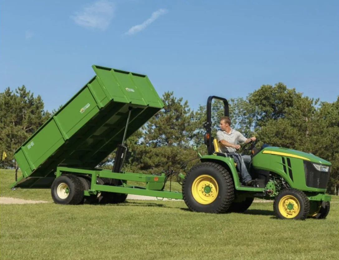 Turf Time DT-12 heavy-duty dump trailer dumping behind a compact tractor